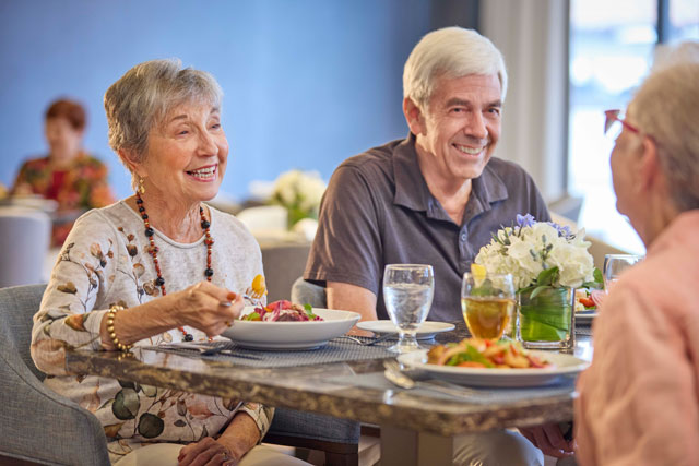 A senior couple relishing their lunch with other residents at Belmont Village's Josephine's Kitchen.